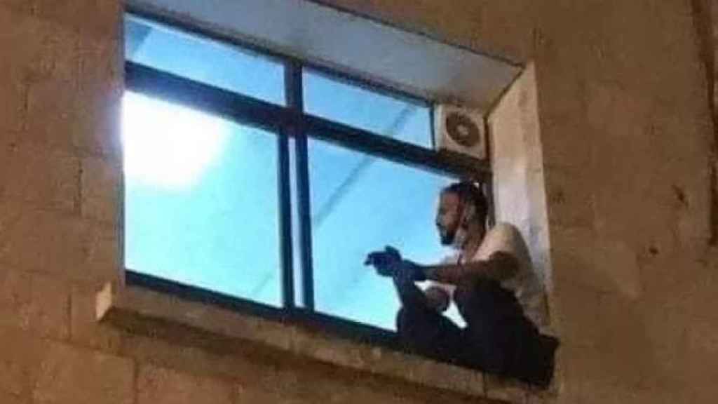 El joven palestino Jihad Al-Suwaiti contemplando a su madre a través de la ventana.