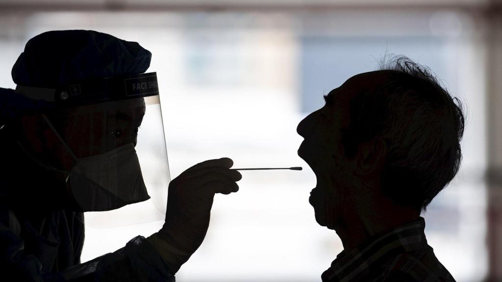 Una sanitaria se prepara a tomar muestras con hisopo del fondo de la garganta de un caso sospechoso. EFE/EPA/Jeroma Favre