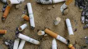 Imagen de varias colillas de cigarrillo en el suelo.