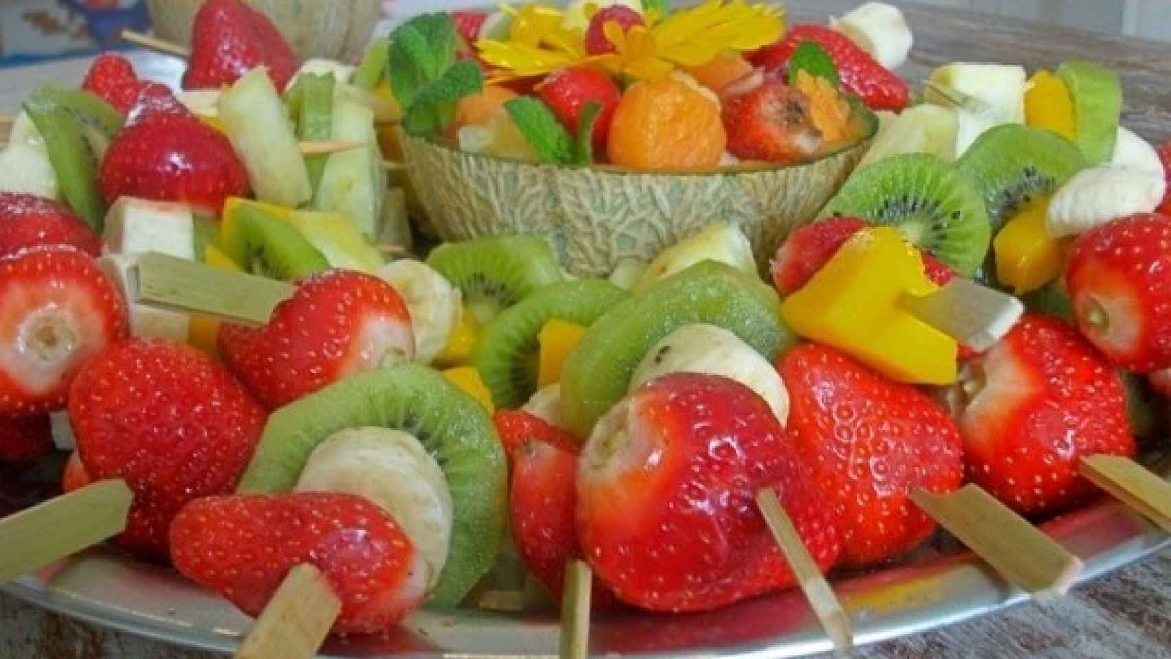 Pinchos de fruta en bandeja rodeando un cuenco