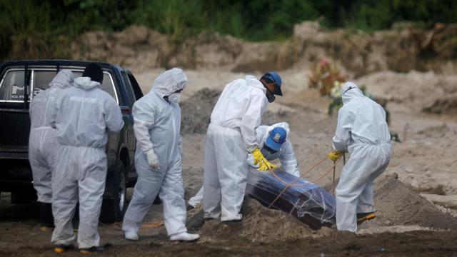 Los trabajadores del cementerio de La Bermeja, en San Salvador, entierran el ataúd de un fallecido por coronavirus.