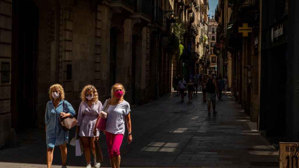 Tres mujeres con mascarilla pasean por el barrio Gótico de Barcelona.