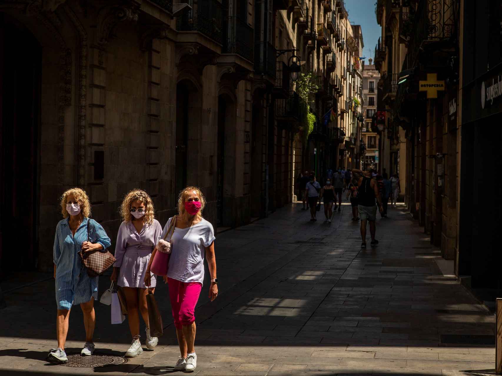 Tres mujeres con mascarilla pasean por el barrio Gótico de Barcelona.
