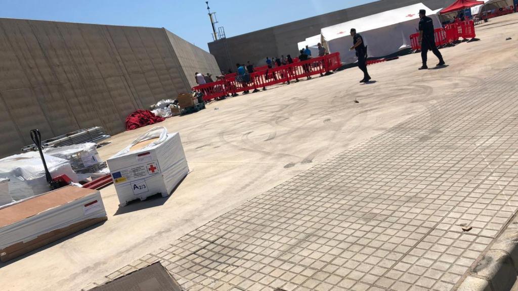Dos policías nacionales custodian bajo un sol a los inmigrantes del campamento de Escombreras.