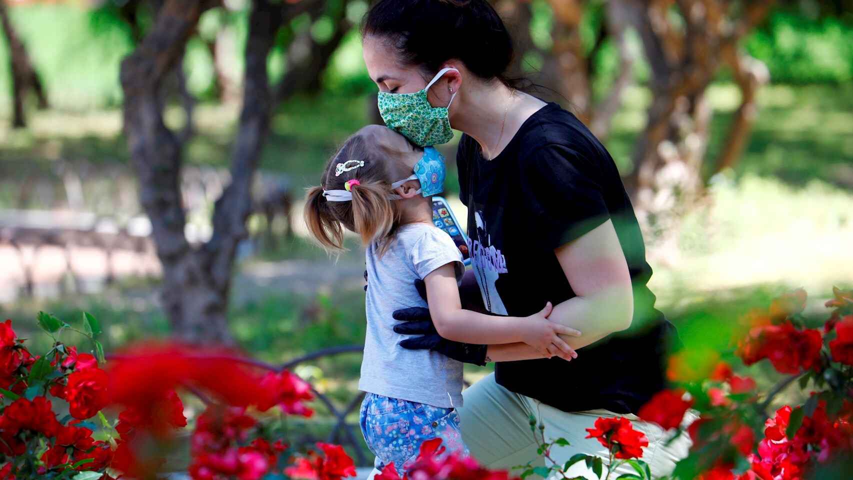 Una madre y su hija, ambas protegidas con mascarillas, en un parque de Córdoba. EFE/Salas