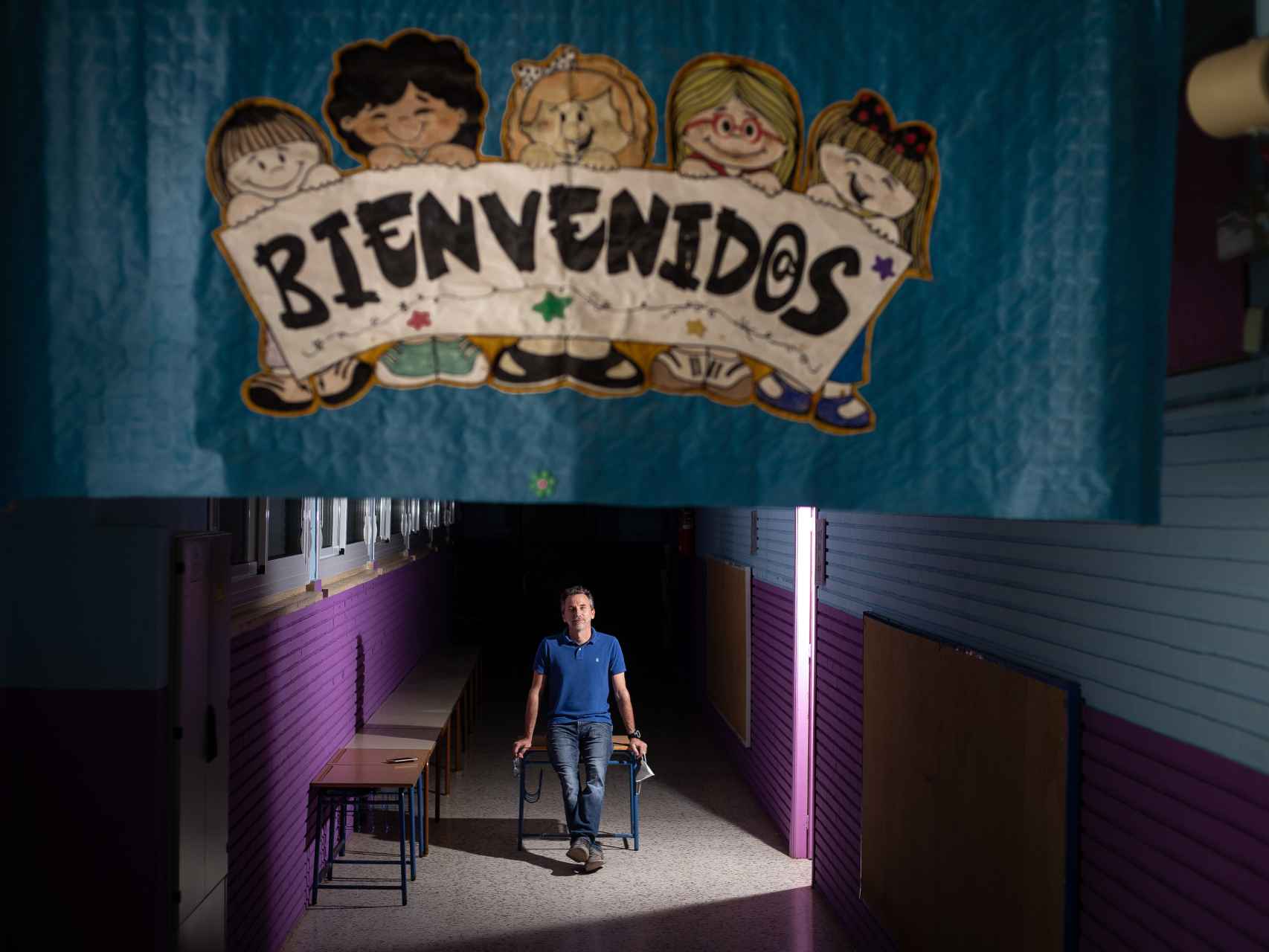 El director de La Paz, tras un cartel de Bienvenidos, en el pasillo de las aulas de Infantil.