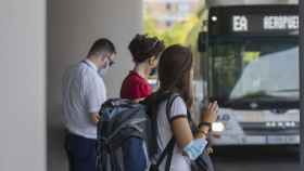 Varias personas en la parada del bus exprés hacia el aeropuerto de Sevilla.