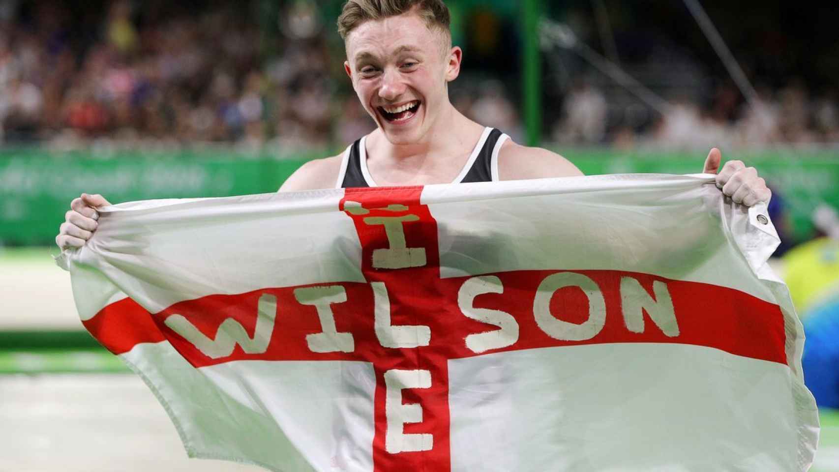 Nile Wilson, con la bandera de Inglaterra tras ganar la medalla en barra fija