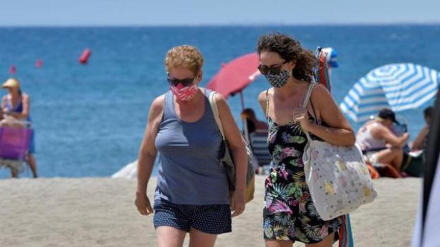 Dos mujeres con mascarilla en la playa.