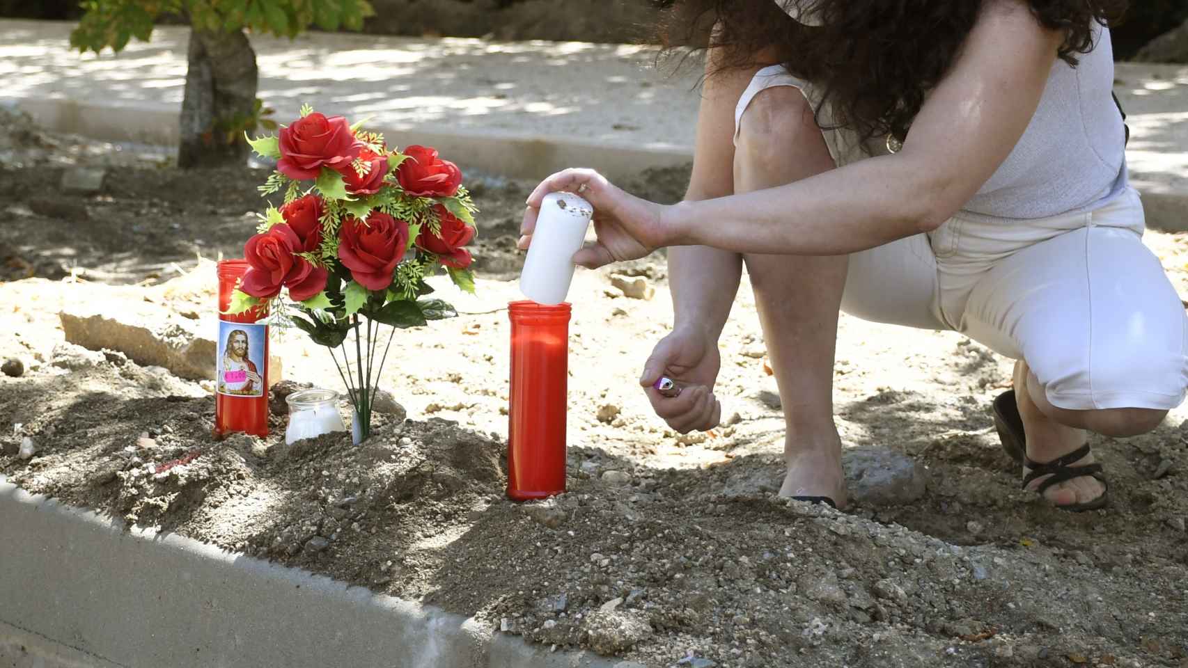 Una mujer enciende una vela junto a un ramo de flores en el lugar donde una mujer ha muerto en Segovia.