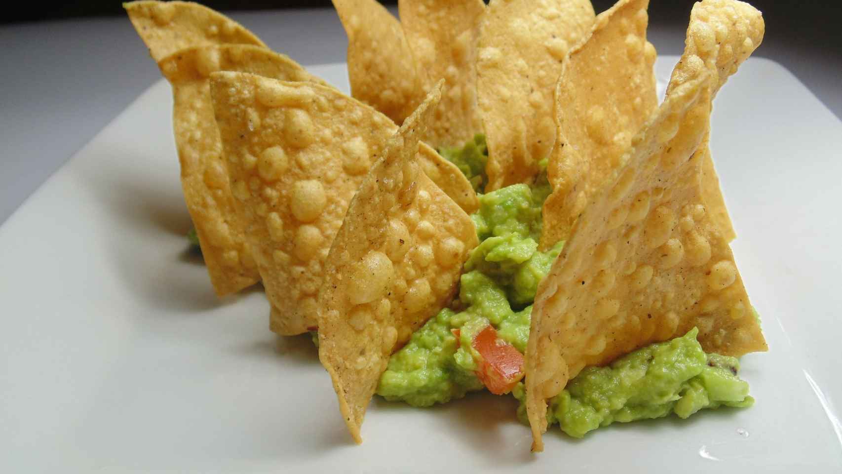 Uno nachos triangulares sobre un poco de guacamole.