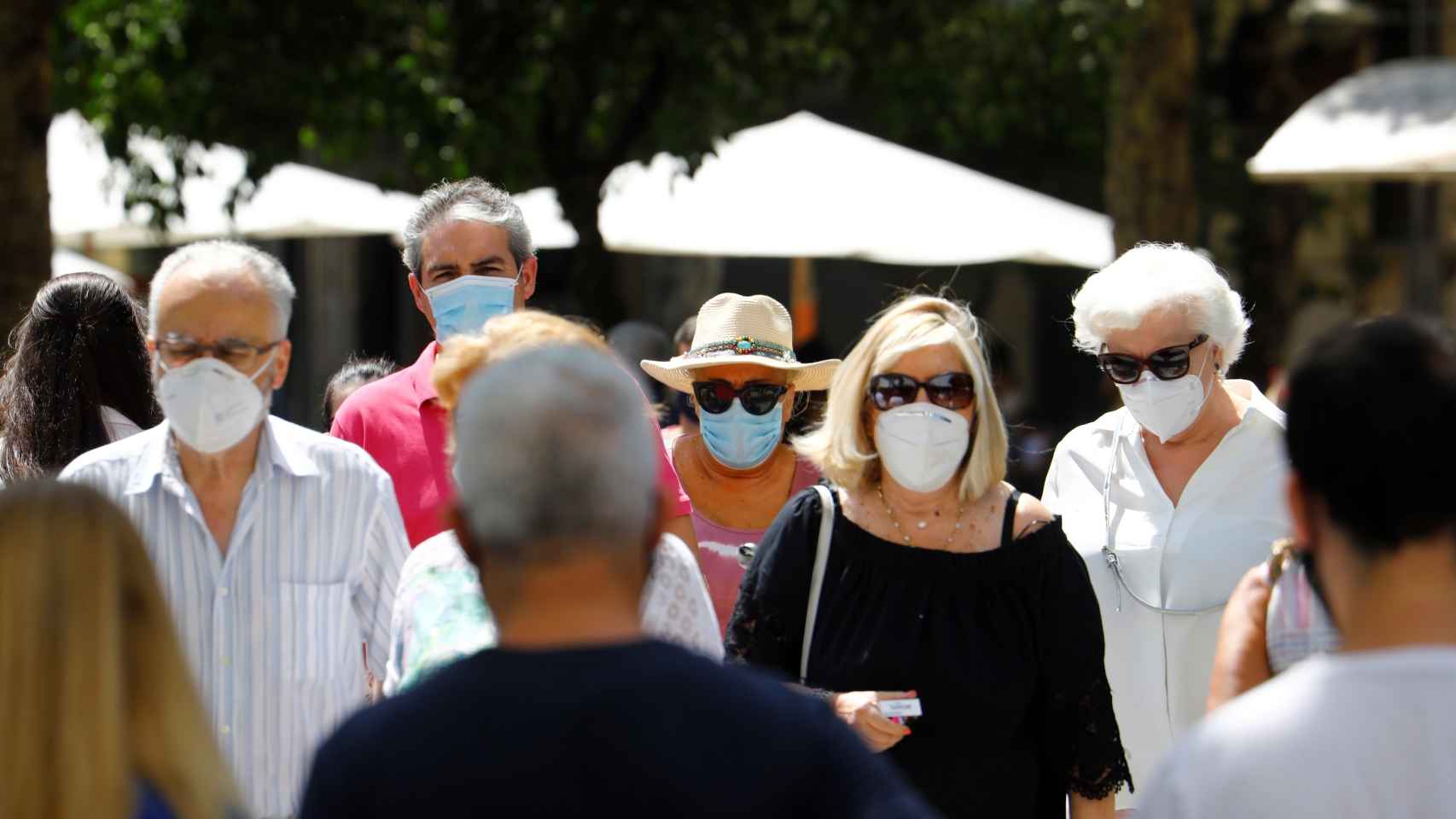 Varias personas caminan por una calle del centro de Córdoba con mascarillas.