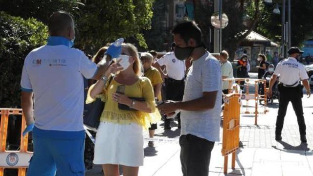 Un paramédico toma la temperatura a un mujer antes de acceder al centro de salud Reyes Católicos,  en Madrid.