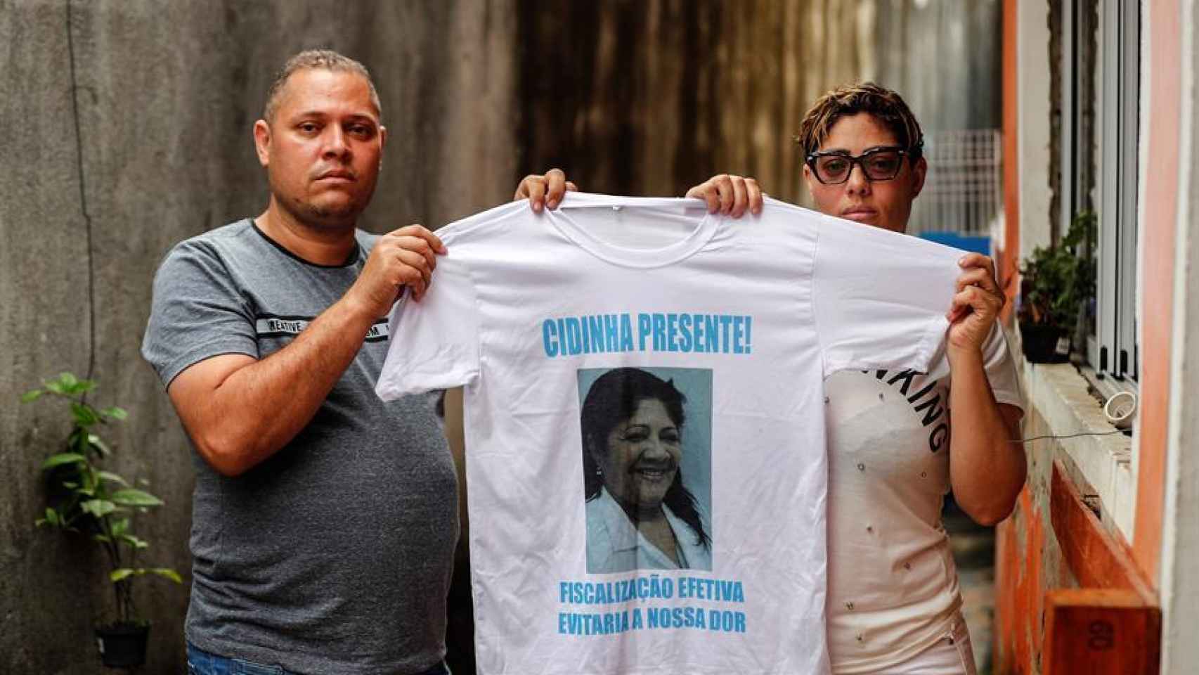 Los hermanos Andreza Reina y Alexandre sostienen una camiseta con la imagen de su madre.