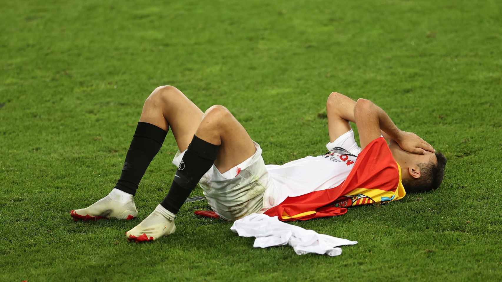 Reguilón, tendido en el suelo con una bandera de España, tras ganar la Europa League con el Sevilla