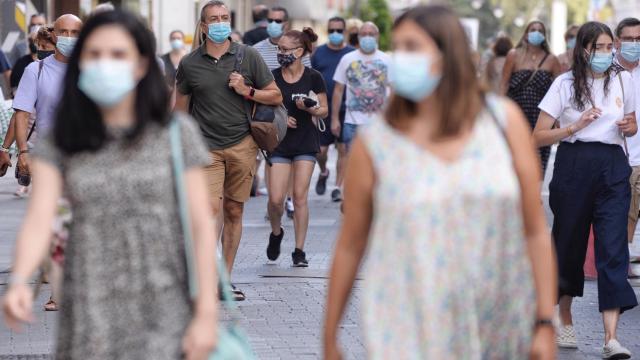 Varias personas caminan con mascarillas.