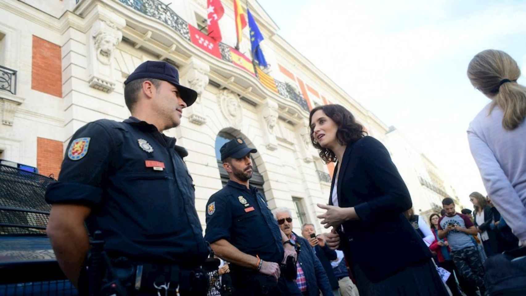 Isabel Díaz Ayuso, presidenta de la Comunidad, saluda a un policía.