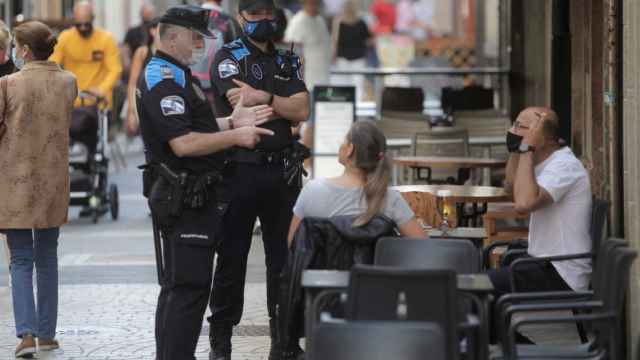 Dos agentes de la policía local de A Coruña se dirigen a un hombre que fumaba en una terraza.