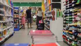 Una pareja acompañada por una niña realiza una compra de material escolar en Valencia.