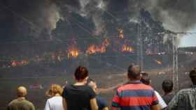 Vecinos de Valverde del Camino observan la labores de extinción del incendio que afecta a la provincia de Huelva.