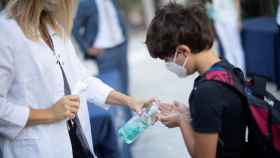 Un niño se desinfecta las manos a la entrada del colegio.