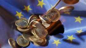 Monedas de euro sobre una bandera de la Unión Europea.
