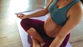 Una embarazada practica yoga en su casa.