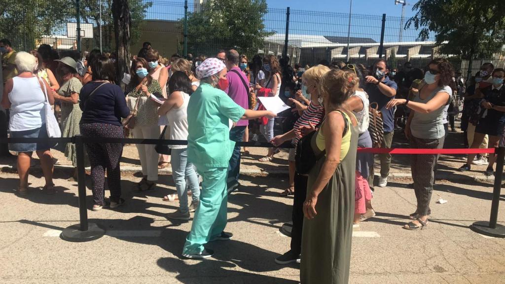 Una enfermera reparte las hojas de consentimiento entre los profesores de la fila.