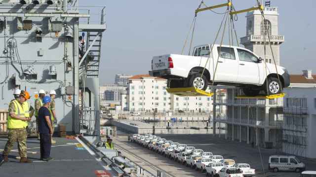 Un coche de la marca Toyota cargado por una grúa en el puerto de Gibraltar.