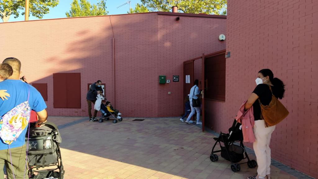 Varios padres, junto a sus hijos, esperan pacientemente a que les autoricen a acceder al centro educativo.
