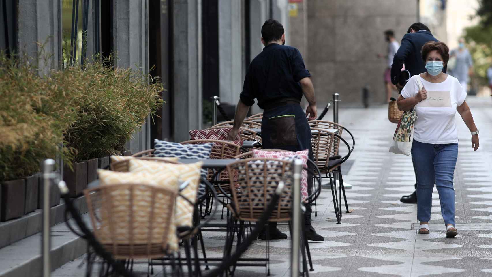 Un camarero prepara una terraza de un bar en Madrid