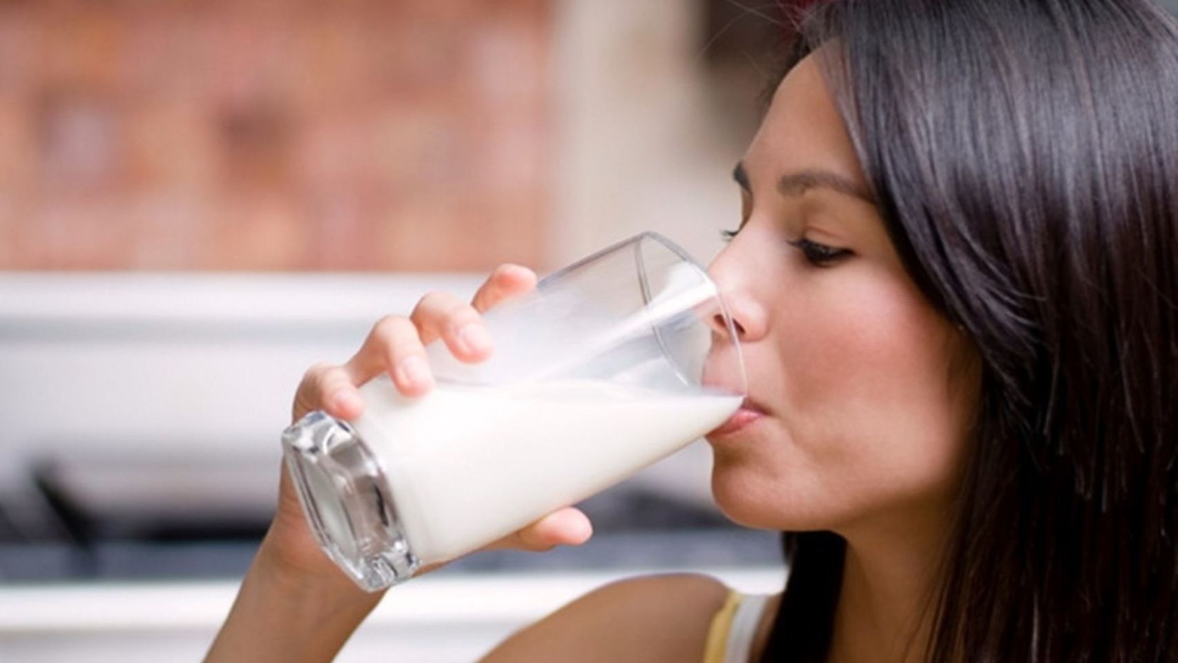 Una mujer bebe un vaso de leche.