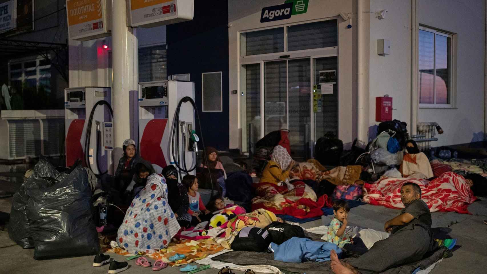 Un grupo de migrantes duerme en una gasolinera tras el incendio del campo de Moria, en la isla de Lesbos