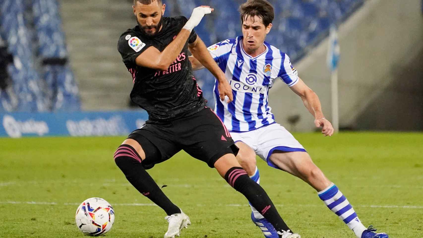 Karim Benzema protege el balón de un jugador de la Real Sociedad