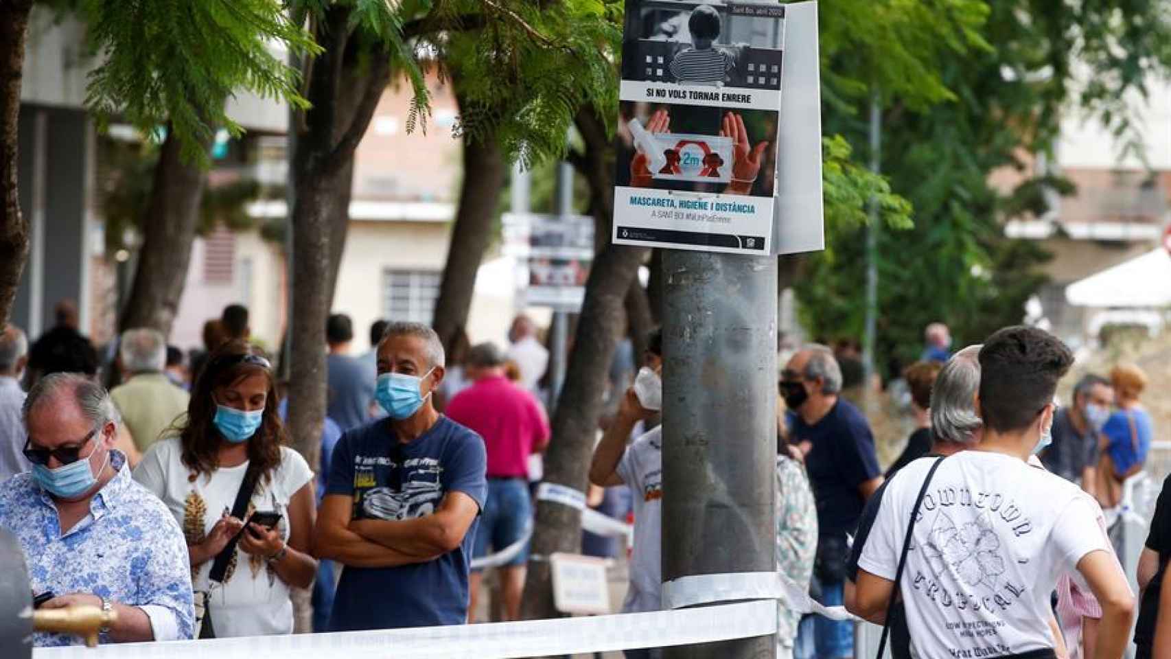 Un cartel informa a las personas que esperan para realizar los cribados masivos de PCR realizados en Sant Boi del Llobregat.