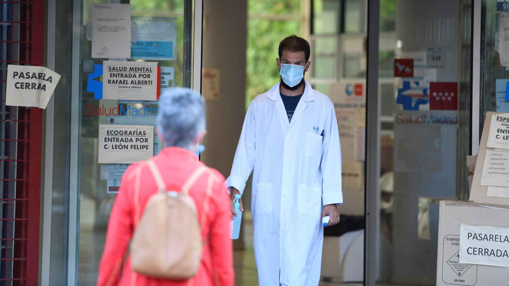 Un sanitario recibe a una paciente termómetro en mano en un centro de salud en Madrid.