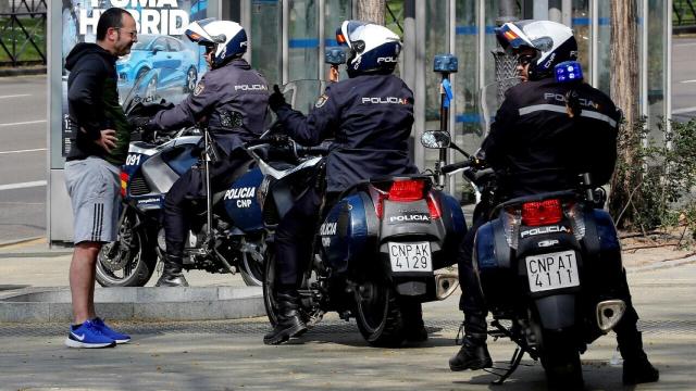 Unos policías llaman la atención a una persona por no llevar mascarilla.