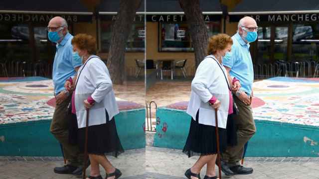 Una pareja de ancianos pasea con mascarilla por las calles de Usera, en Madrid.