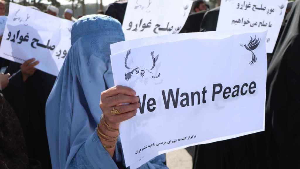 Mujeres afganas sostienen pancartas mientras se manifiestan para apoyar las conversaciones de paz de Doha.