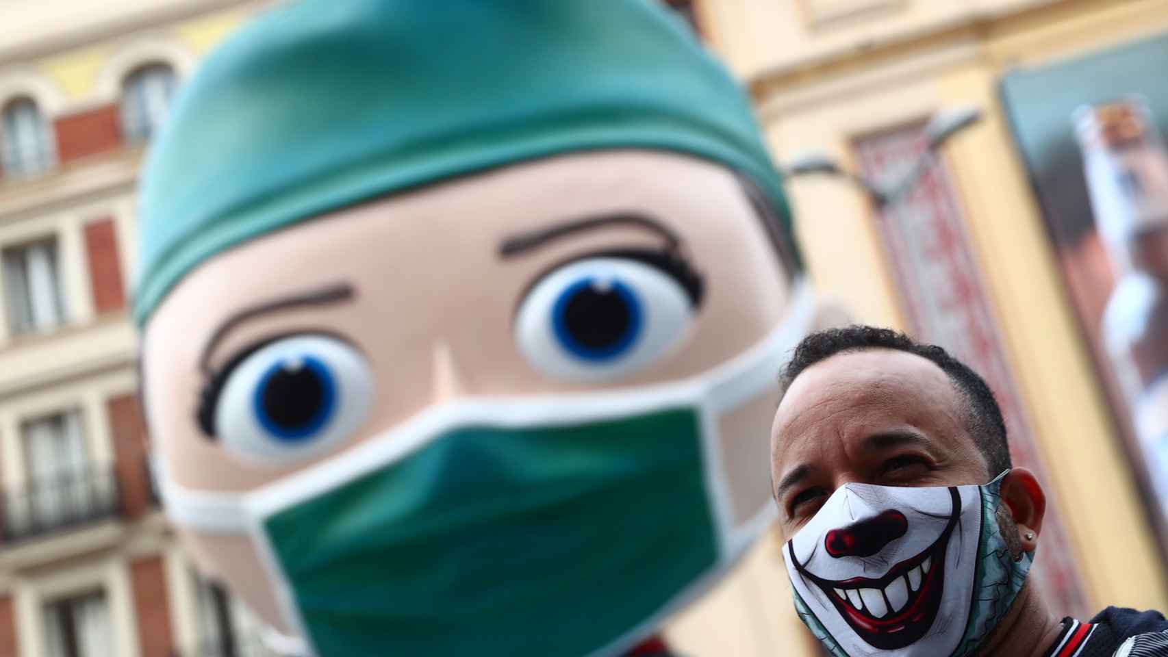 Una persona con una mascarilla decorada junto a la figura del 'súper sanitaria' de Callao. Reuters/Sergio Pérez