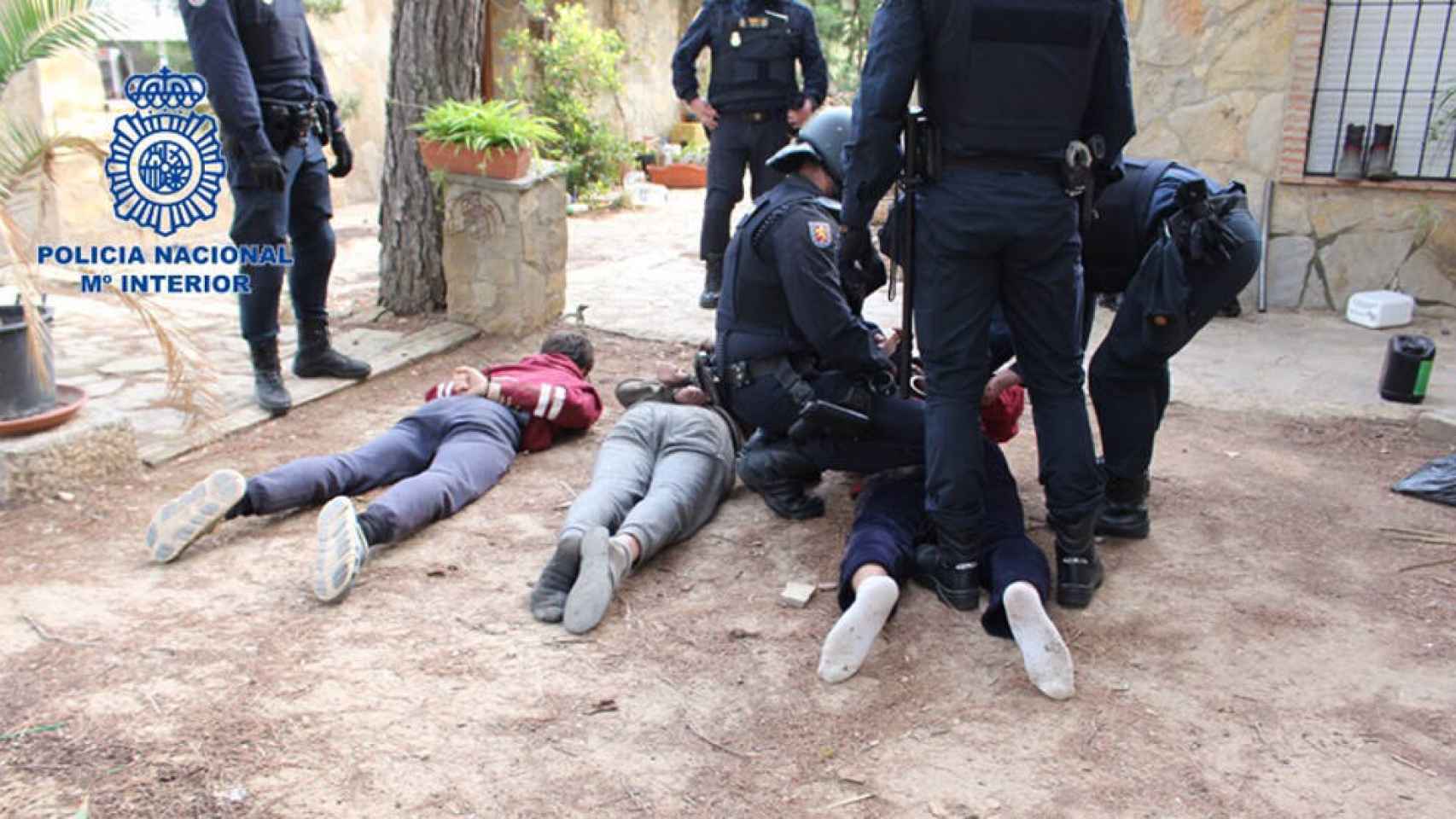 Los tres detenidos, en el suelo y custodiados por la Policía Nacional