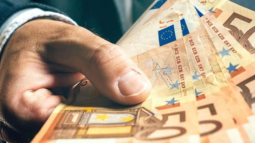Una mano extiende billetes de 50 euros.