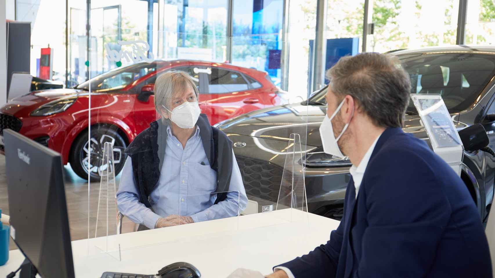 Imagen de un usuario en un concesionario interesándose por un coche nuevo.