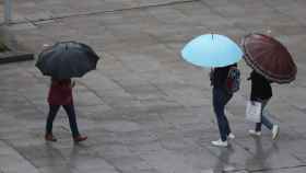 Unos viandantes se protegen de la lluvia traída por la tormenta Álex en Bilbao.