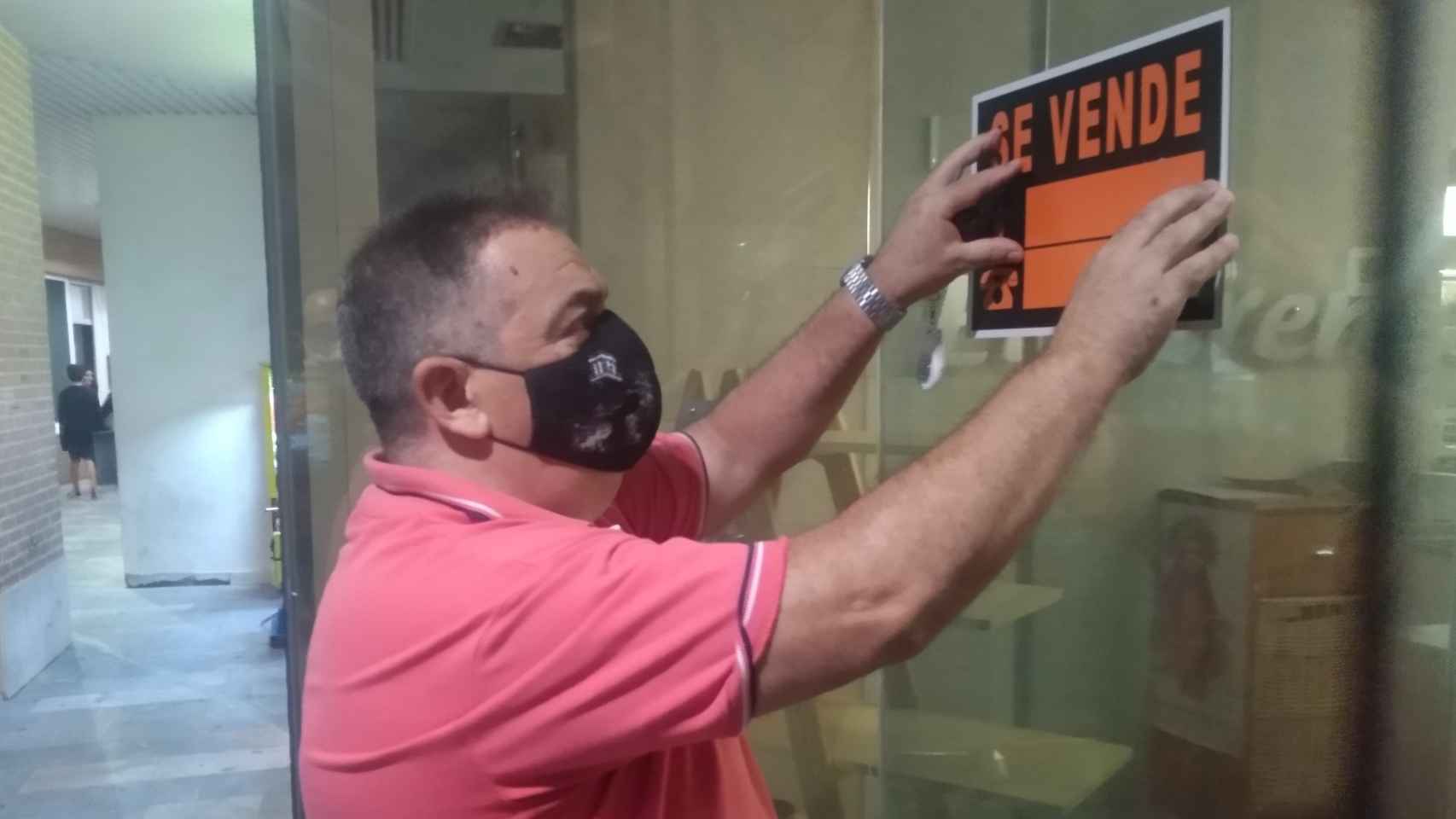 Pepe Martínez, fijando el cartel de 'Se Vende' en su negocio, la Cafetería El Sereno.