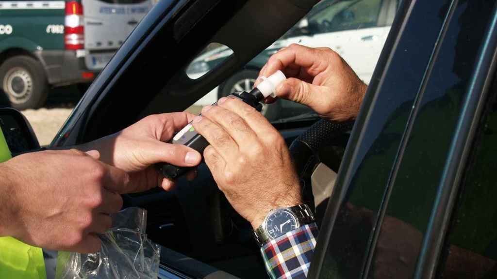 Un agente realizando un test de alcoholemia a un conductor.