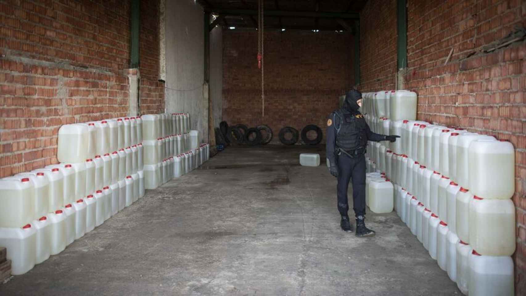 Un agente de la Guardia Civil cuenta el número de bidones de gasolina incautados en una nave de Lebrija (Sevilla).