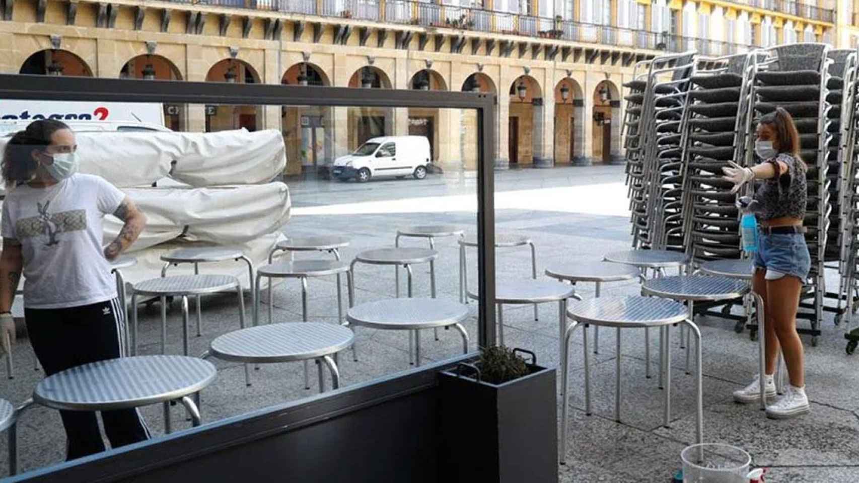 Empleadas de un bar  de Cataluña preparan una terraza.