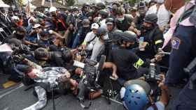 Manifestantes y periodistas caen al suelo durante una manifestación.