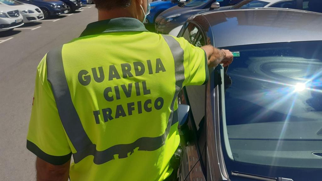 Un agente de la Guardia Civil comprobando si la pegatina de la ITV de un coche está vigente.